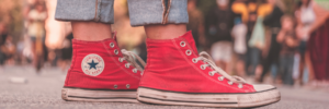 The feet of a person wearing red converse high tops