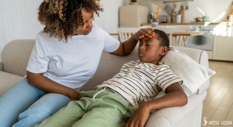 mother holding her child's head as he lays on a couch