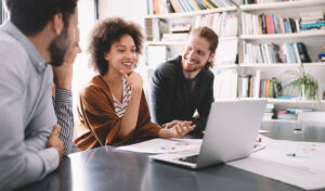 Three people around a laptop working together.