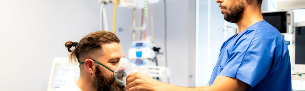 Nurse assisting patient by placing oxygen mask on his face in hospital room