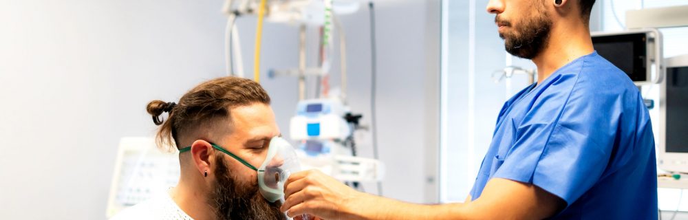Nurse assisting patient by placing oxygen mask on his face in hospital room