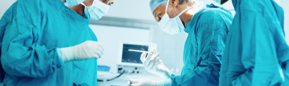 Surgeons in blue gowns leaning over hospital bed.