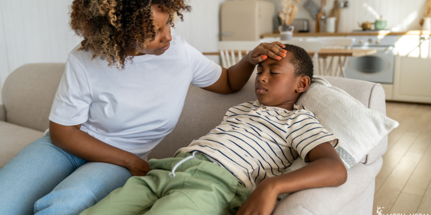 mother holding her child's head as he lays on a couch