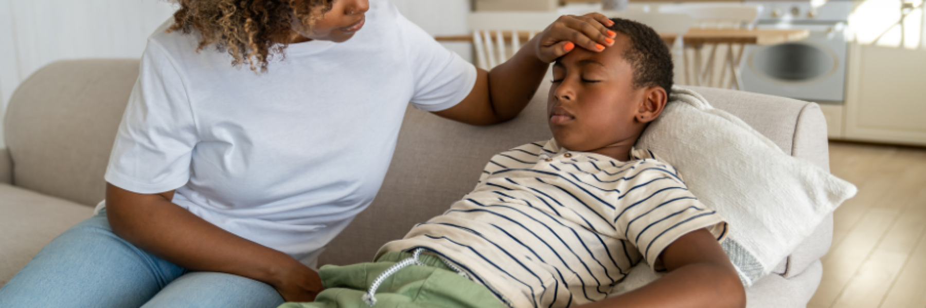 mother holding her child's head as he lays on a couch