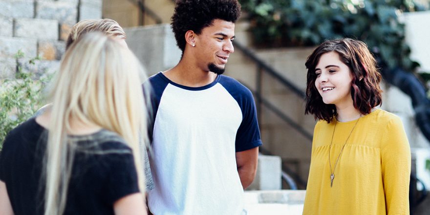 A group of teenagers, smiling in conversation