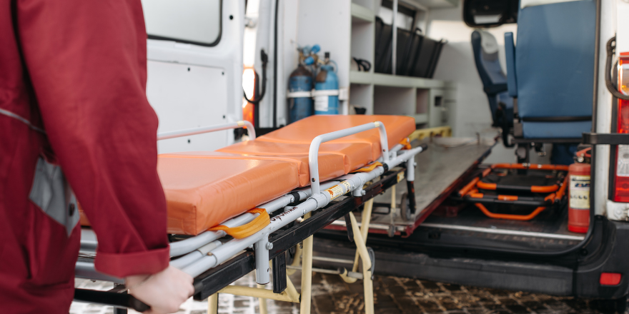 Paramedic pushing an empty stretcher into an ambulance