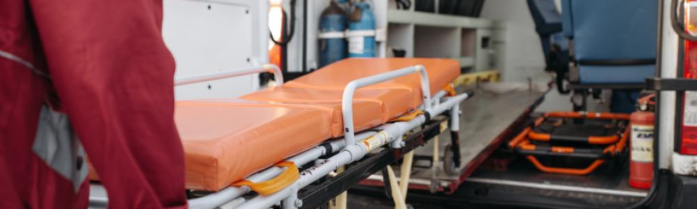 Paramedic pushing an empty stretcher into an ambulance