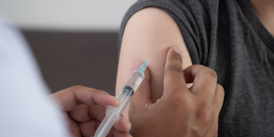 A person receiving a vaccination. Syringe in healthcare workers hands